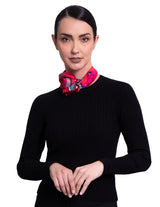 A woman wearing A square silk scarf featuring a vibrant, multicolored abstract floral and geometric print.
