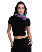 Woman wearing a black crop top and black pants with a colorful scarf around her neck